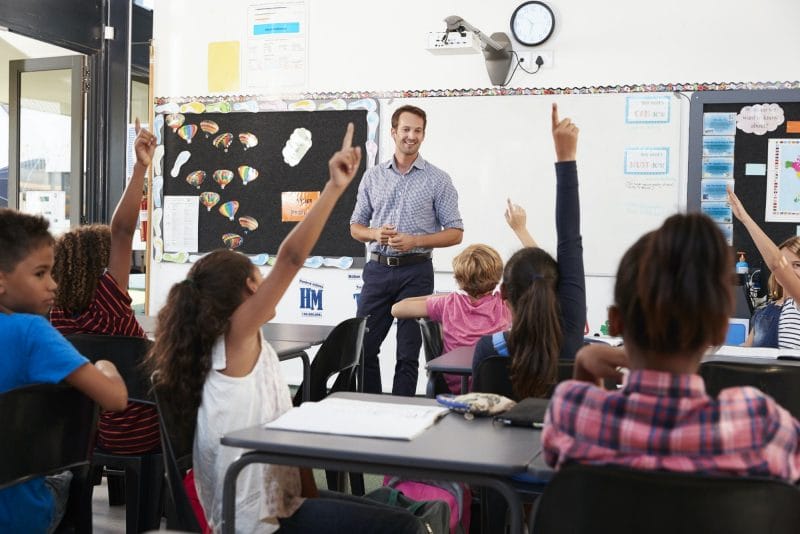 School kids raising hands in elementary school class