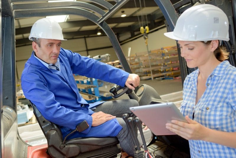Woman using tablet next to man on forklift